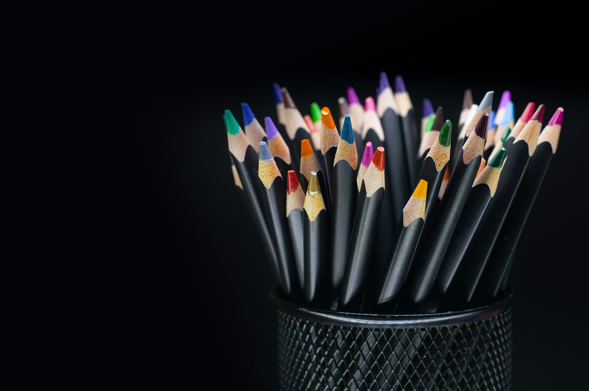 Lápices de colores con puntas afiladas sobre fondo oscuro.